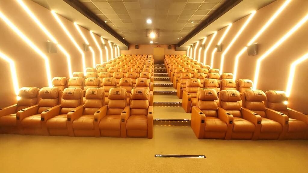 Cineverse Multiplex NCS Mall auditorium with tan leather recliners and gold chevron wall lighting