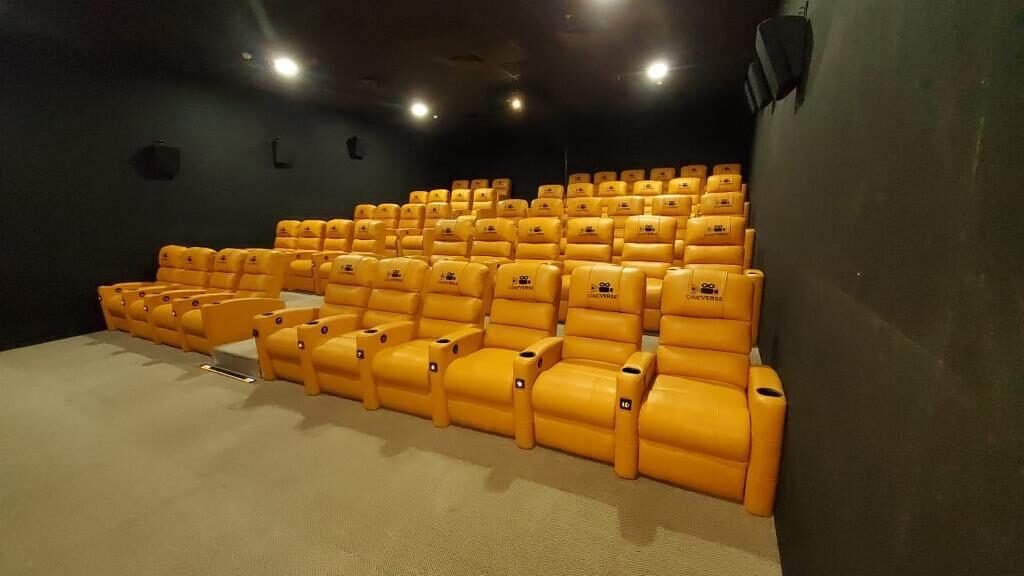 Rows of saffron leather Cineverse recliners with cup holders and branded headrests